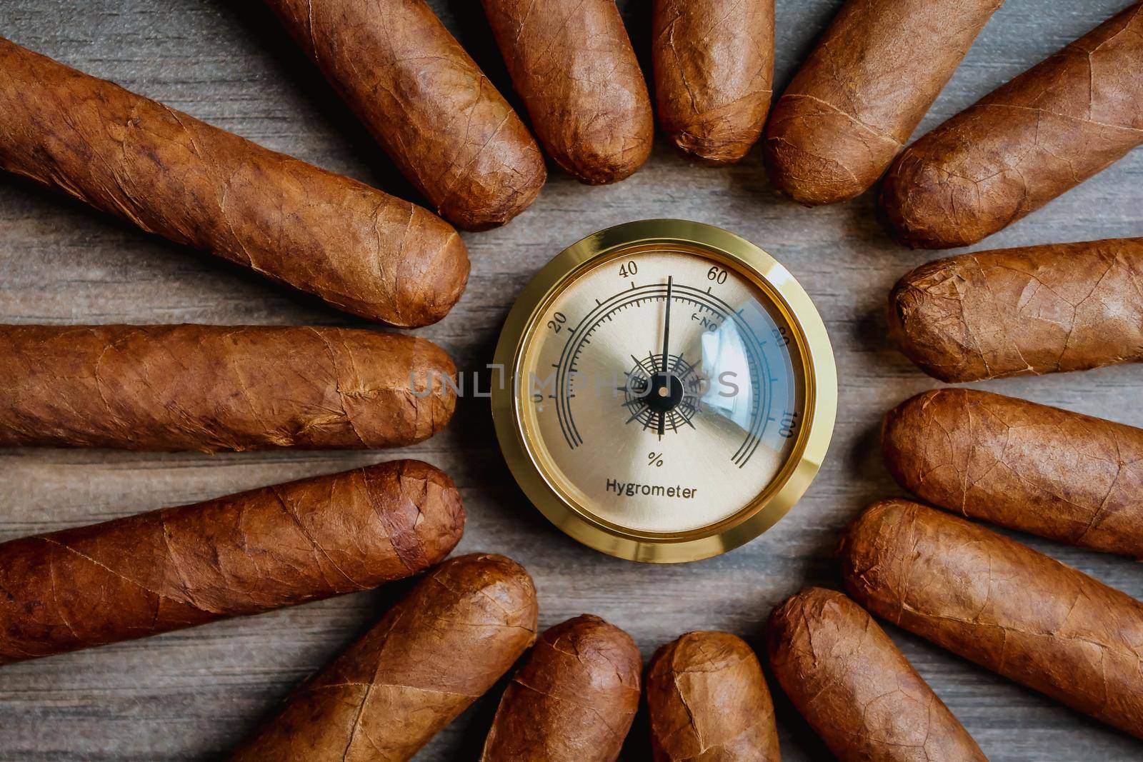 Pile of cigars with humidor hygrometer on the wooden background