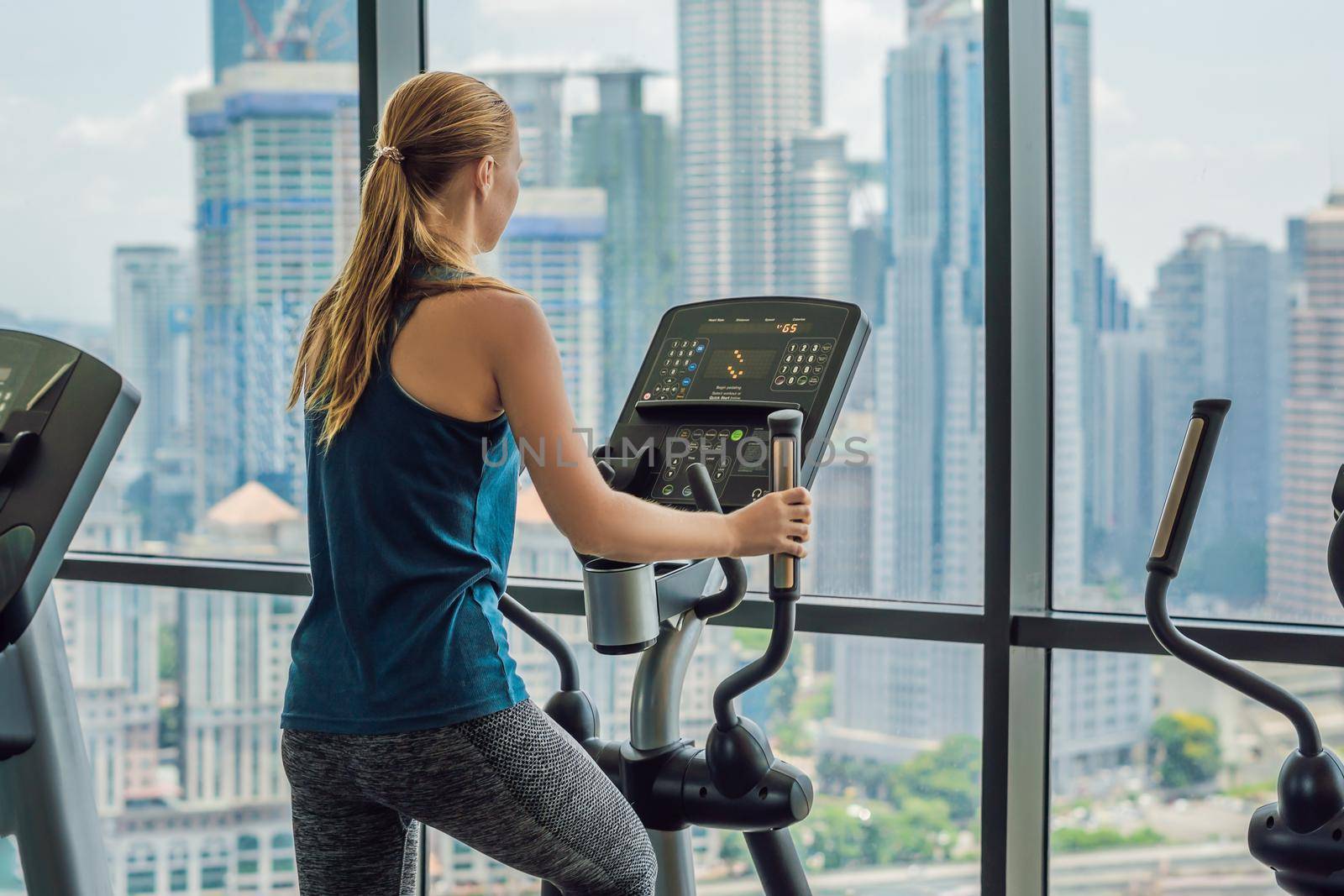 Concept of sport and healthy lifestyle. Strong young beautiful woman is engaged in a gym on an ellipsoid.