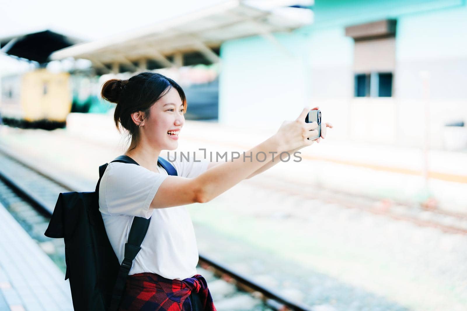 summer, relax, vacation, travel, portrait of beautiful Asian girl using the smartphone mobile take a photo selfie face yourself at the train station while waiting for their travel time