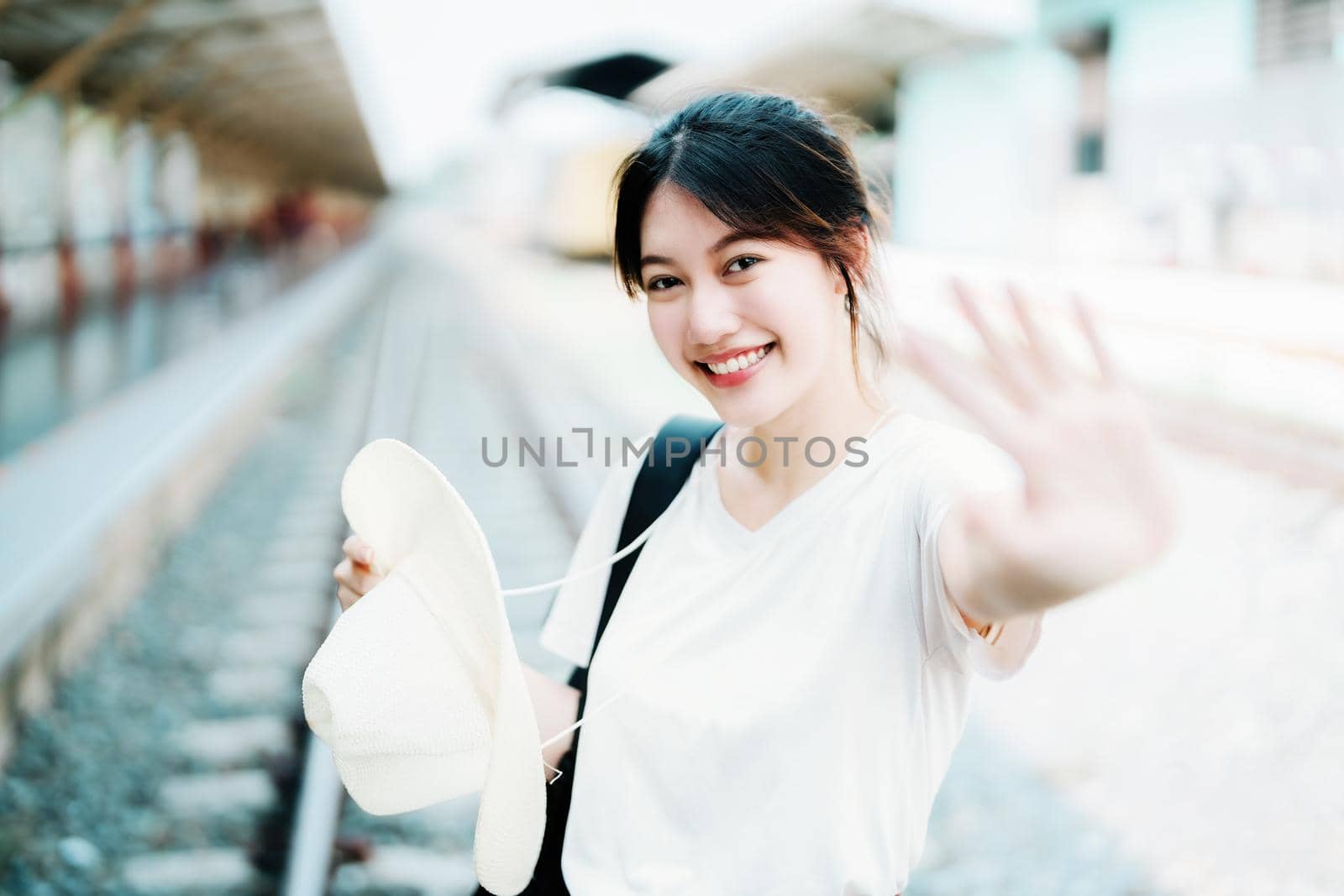 summer, relax, vacation, travel, portrait of cute Asian girl showing smile and showing joy while waiting at the train station for a summer trip