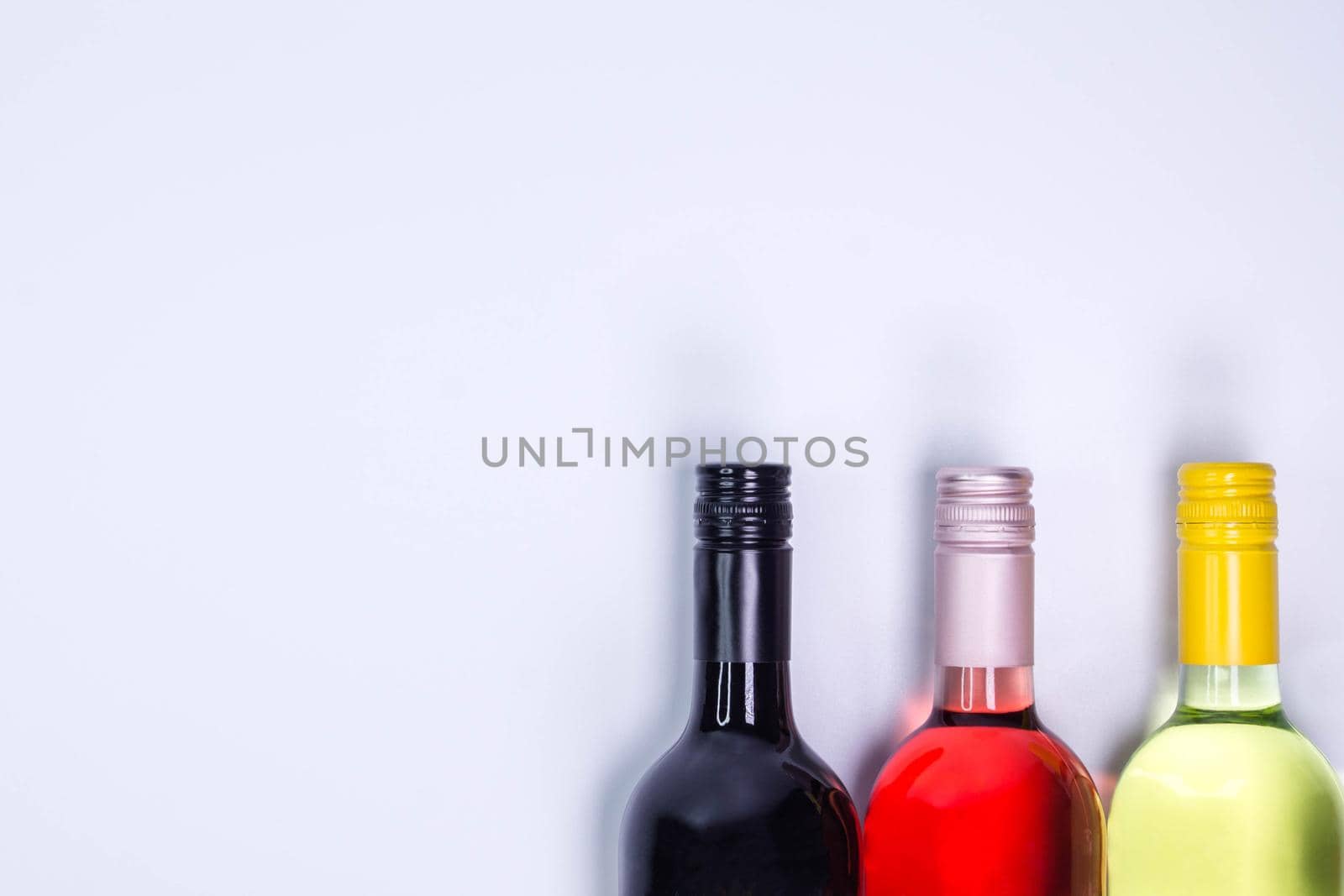 Red, rose and white wine bottles on white table. Top view with copy space. Space for text. Wine bottle necks by JuliaDorian