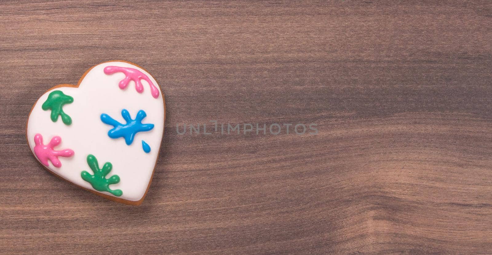 Colorful heart shaped glazed cookie for Valentine's day on wooden background. Paint splatter. Space for text. Easter cookie by JuliaDorian
