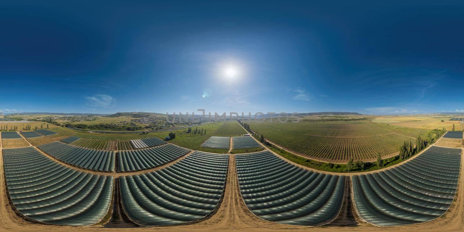 Aerial drone view of huge areas greenhouse for growing vegetables. Greenhouse farming, agriculture industry. Flying over large industrial greenhouses at sunset