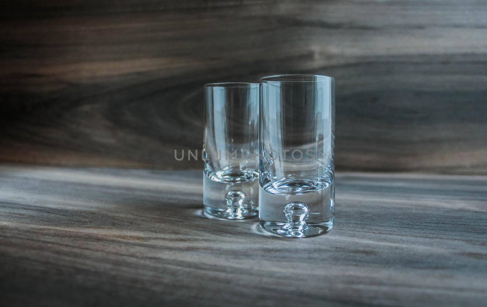Two empty shot glasses on a wooden background