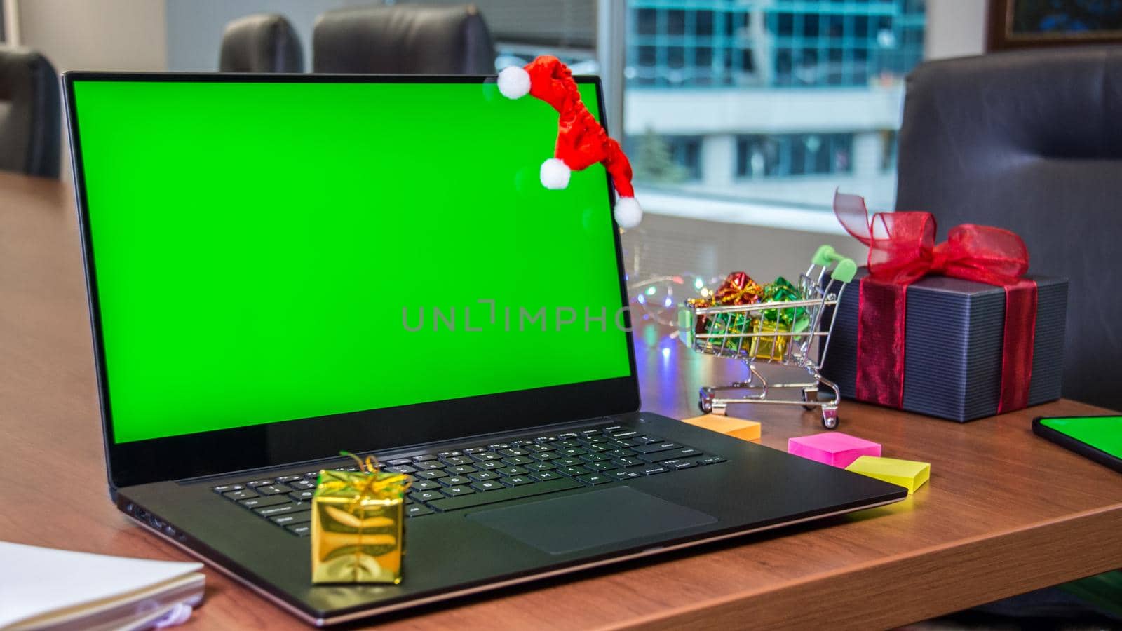 Laptop with green screen mockup, shopping cart full of gifts on background. Online shopping. by JuliaDorian