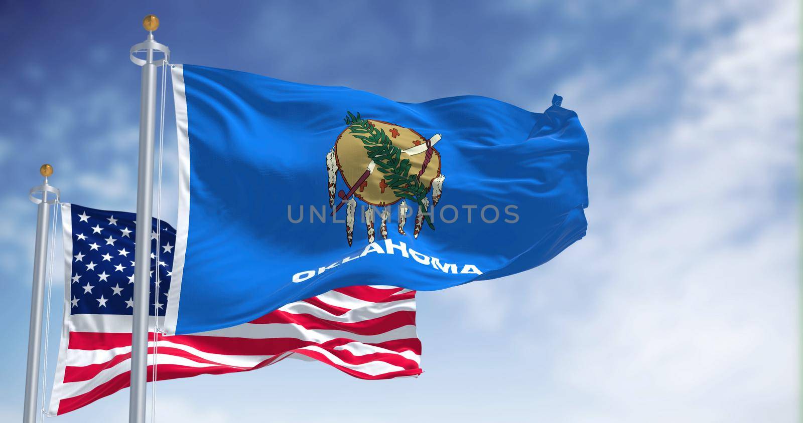 The Oklahoma state flag waving along with the national flag of the United States of America. Oklahoma is a state in the South Central region of the United States