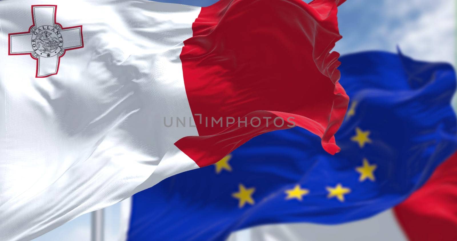 Detail of the national flag of Malta waving in the wind with blurred european union flag in the background on a clear day. Democracy and politics. European country. Selective focus.