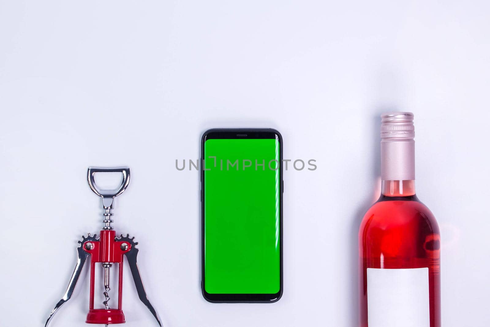 Rose and with corkscrew on white table. Mockup phone. Red wine and steel wine opener. Green screen. Top view with copy space. Space for text. Wine bottle necks by JuliaDorian