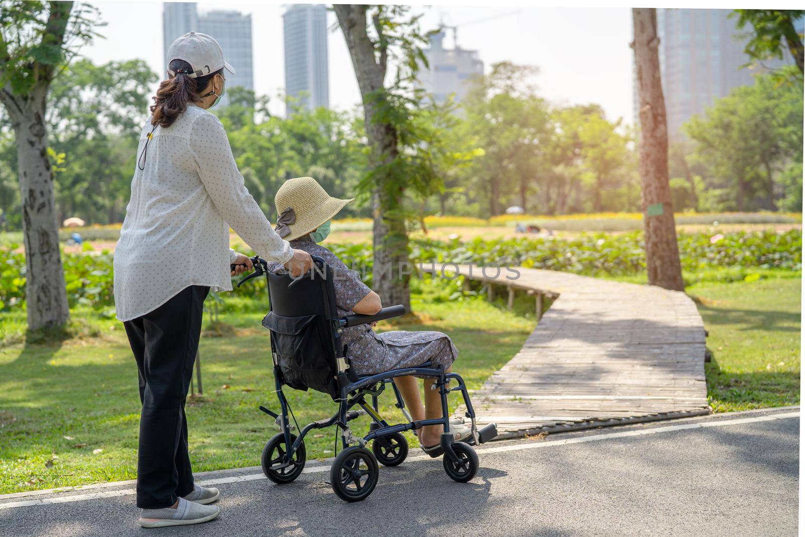 Caregiver help and care Asian senior or elderly old lady woman patient sitting on wheelchair in park, healthy strong medical concept. by pamai