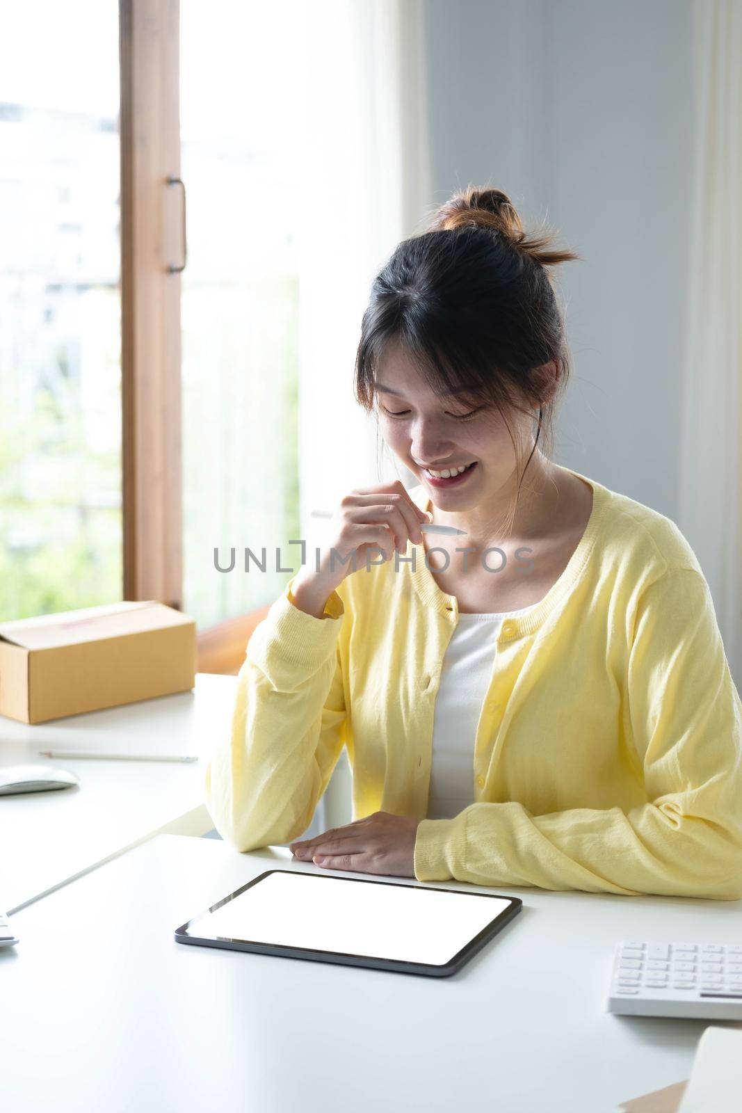 Portrait business Asian woman smile and use tablet checking information on parcel shipping box before send to customer. Entrepreneur small business working at home. SME business online marketing..