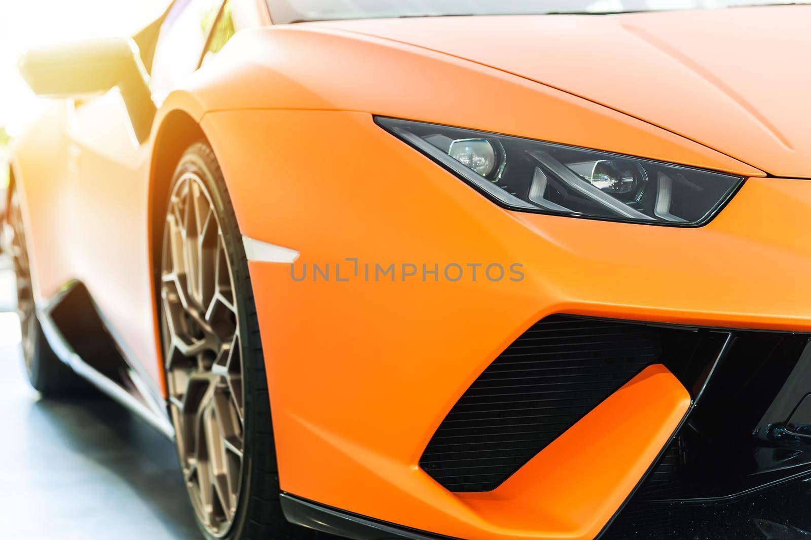 Front of an orange sport luxury car in sunset background