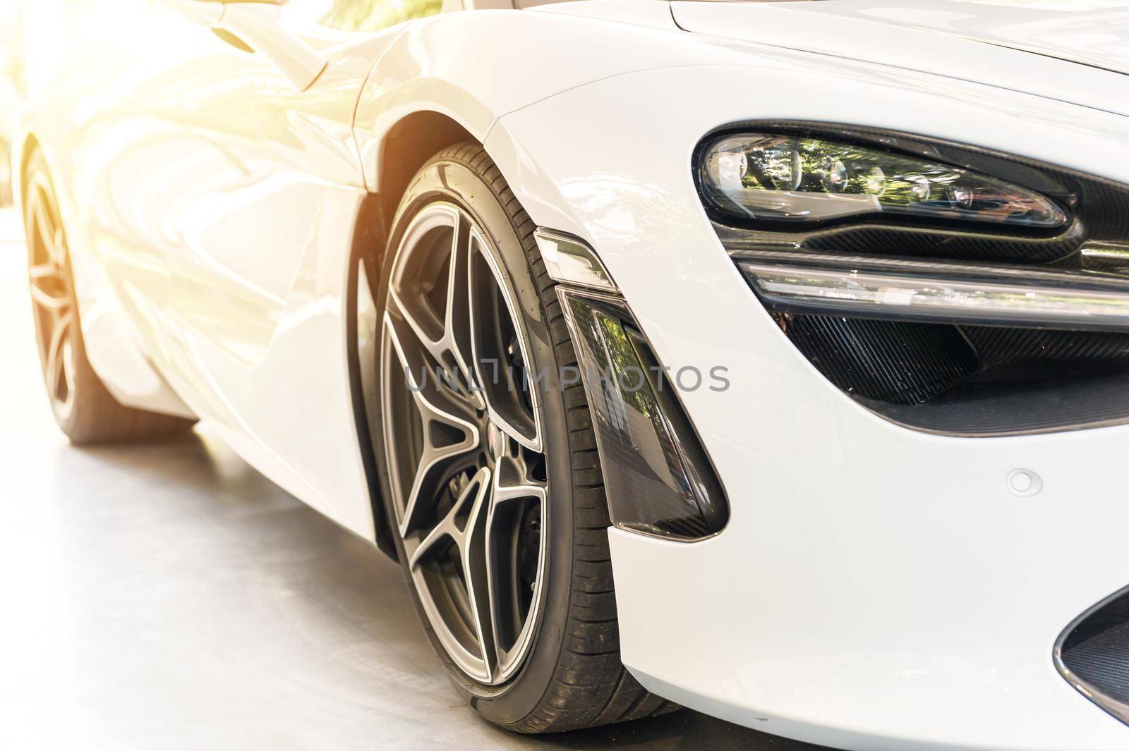 Front of a white sport luxury car in sunset background