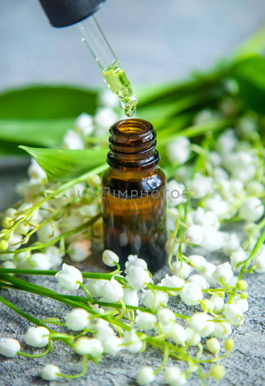 Lily of the valley essential oil in a small bottle. Selective focus. Nature.