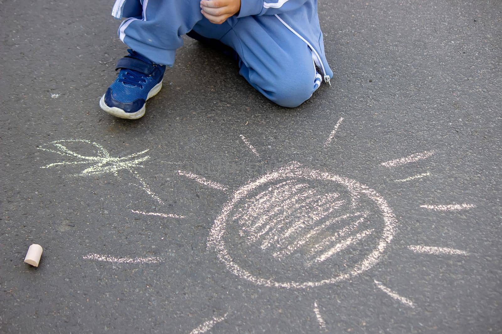 Cute little child draws the sun with chalk outdoors, summer time, chalk. Selective focus. Nature