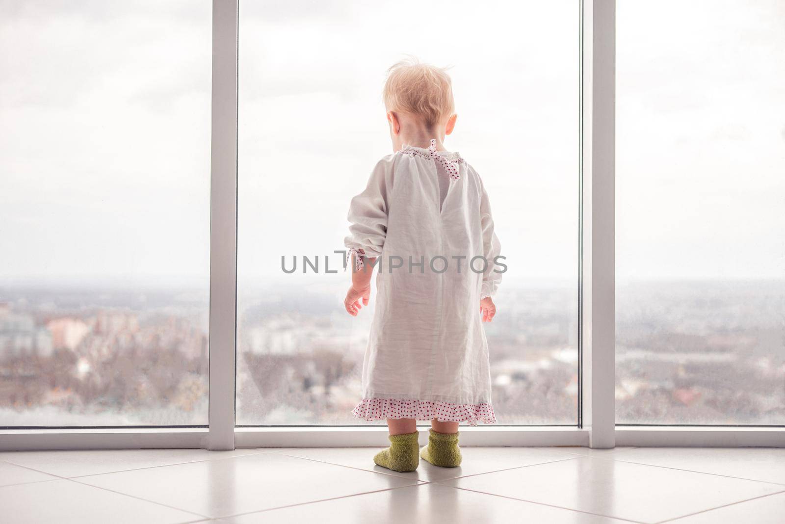 Beautiful little child. Little cute toddler looking at the large window