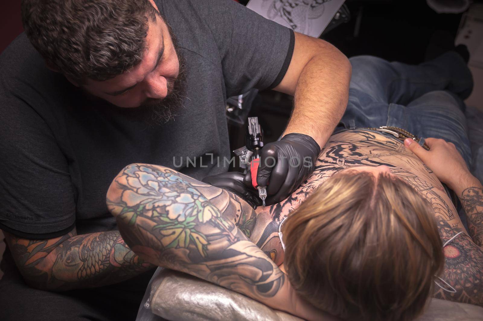 Professional tattoo artist working on professional tattoo machine gun in salon.