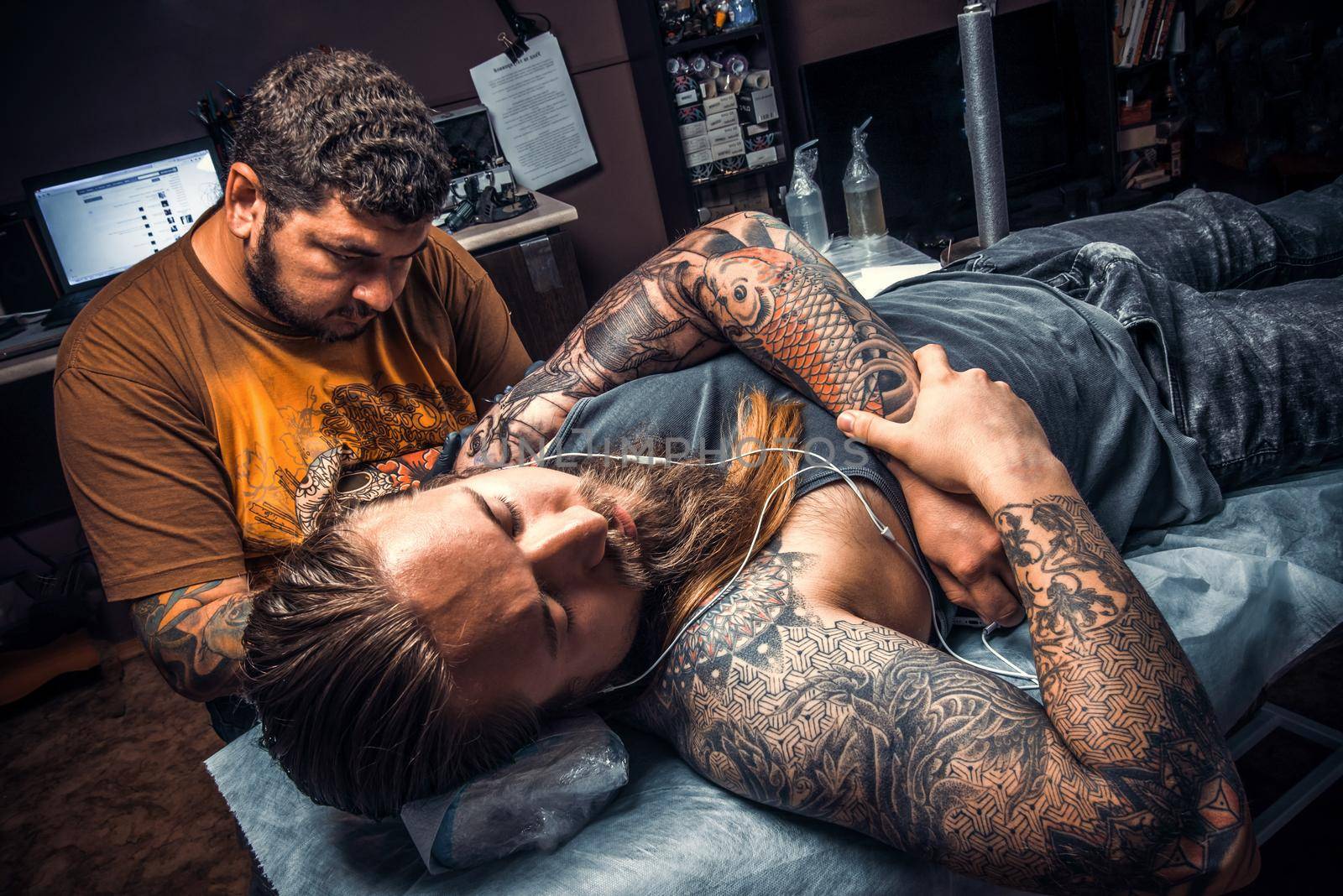 Tattooer makes tattoo pictures in tattoo parlor./Professional tattooist posing in tattoo studio.