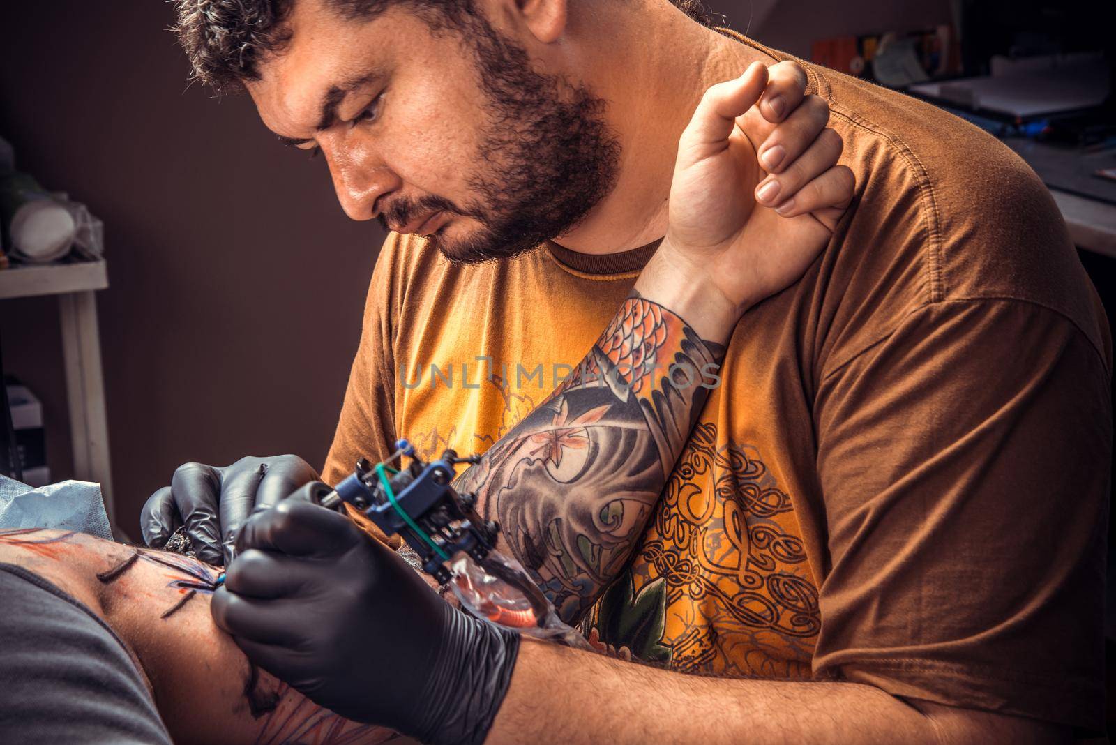 Professional tattooist showing process of making a tattoo in tattoo studio./Professional tattooist works in tatoo salon.