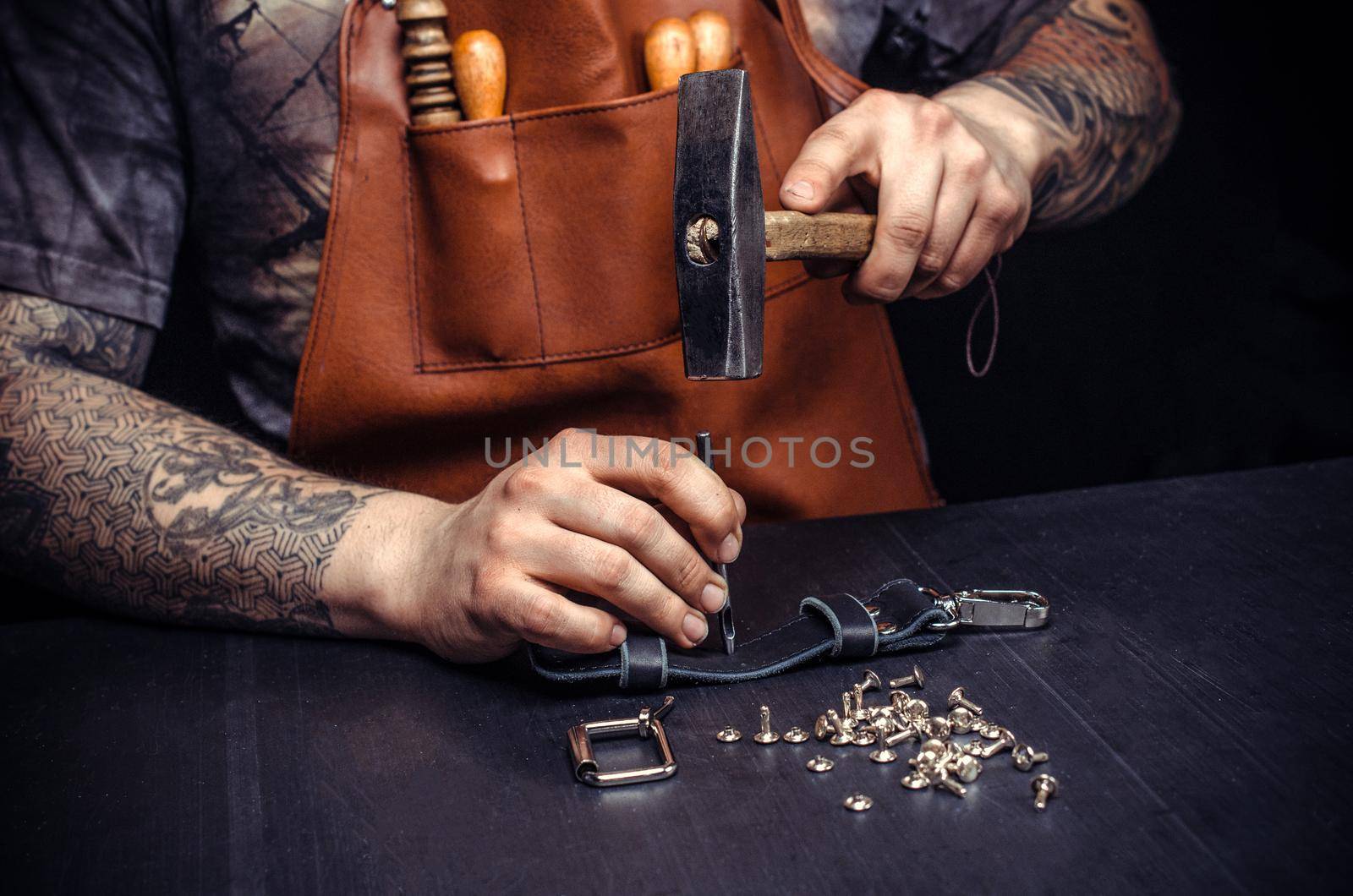 Handyman creating leatherwork at his workplace. Leather Craftsman producing leather workpiece in his leather shop.