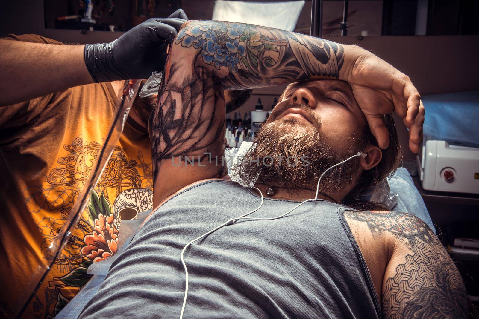 Tattoo specialist showing process of making a tattoo in tatoo salon./Professional tattoo artist doing tattoo in tattoo studio.