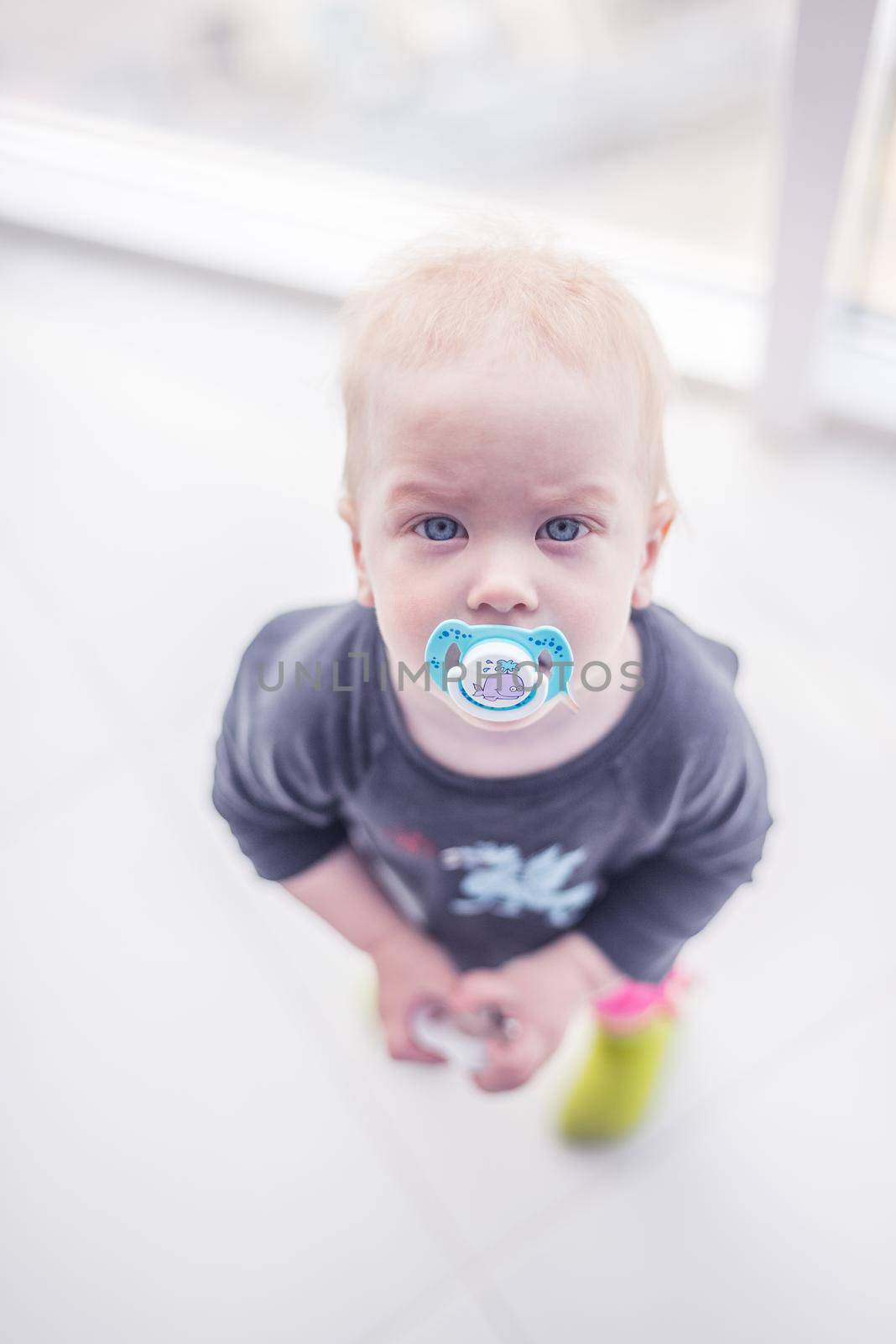 little boy with blue eyes with a pacifier looking at the camera, white background, view from above / cute kids / joy of motherhood