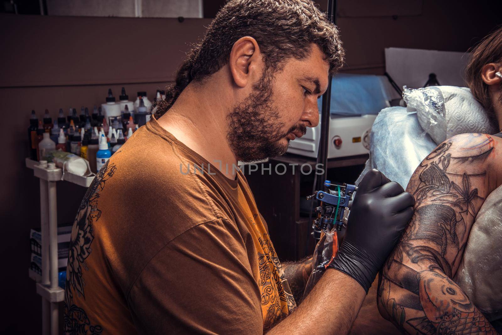 Professional tattooist works in tatoo salon/Tattooist showing process of making a tattoo in tattoo studio.