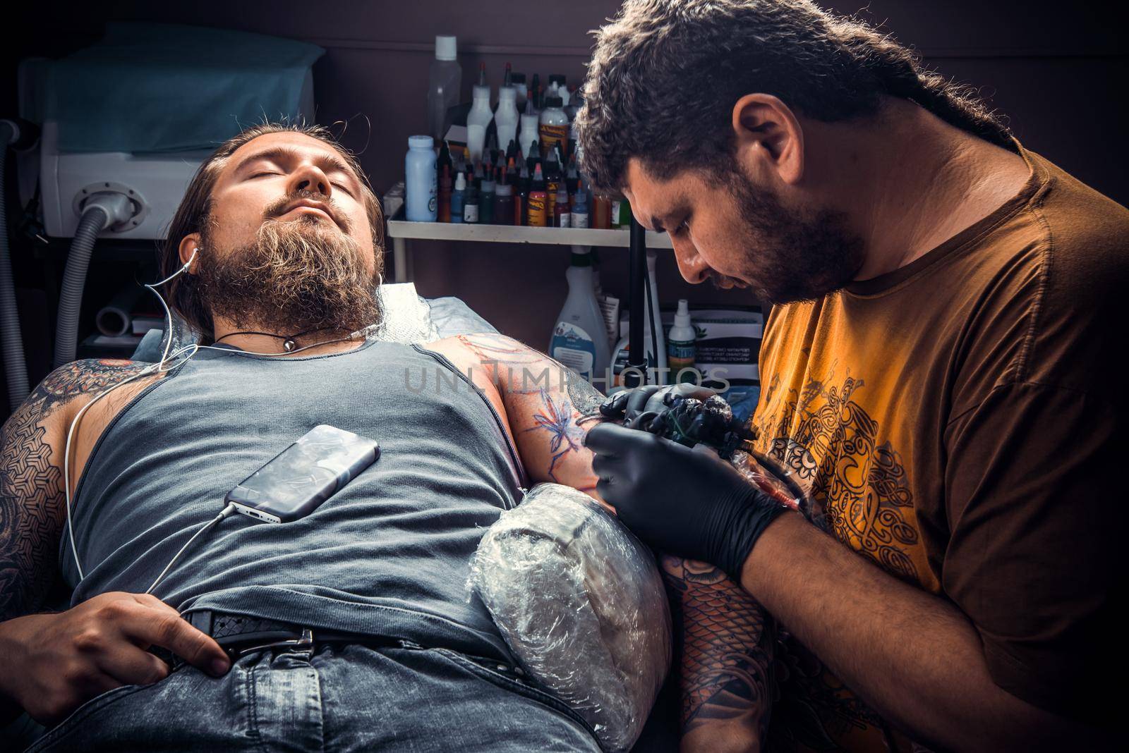 Tattooer posing in tattoo parlour./Professional tattooist makes cool tattoo in studio.