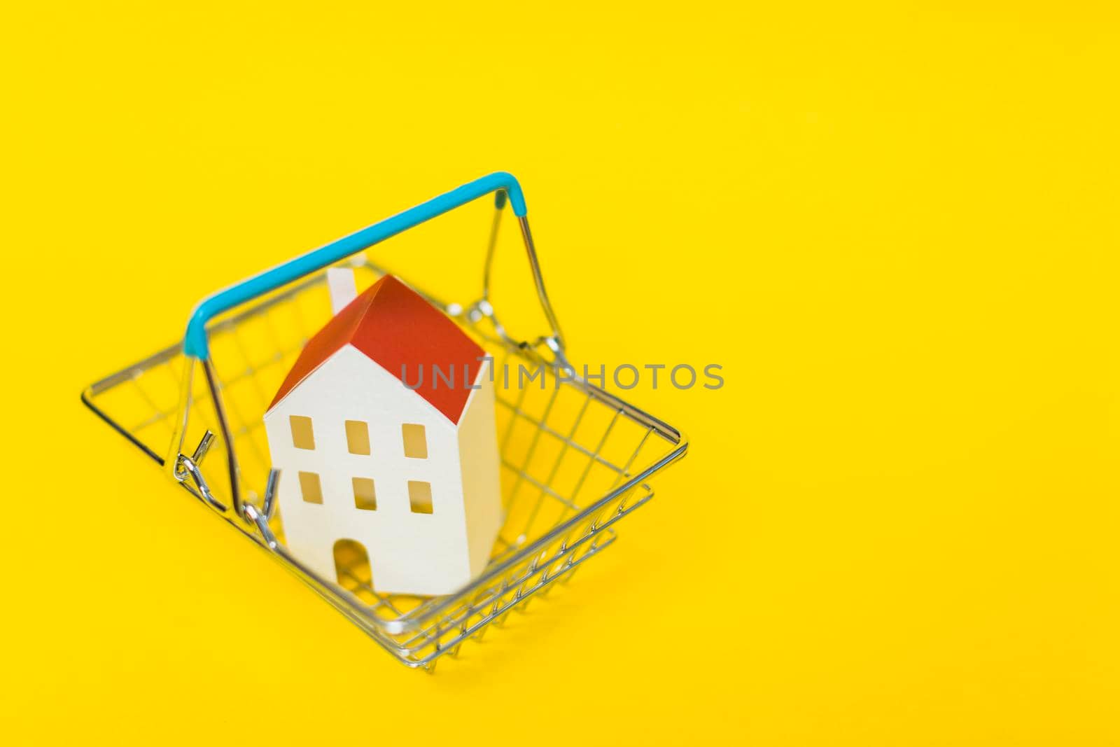 overhead view house model inside shopping cart against yellow background