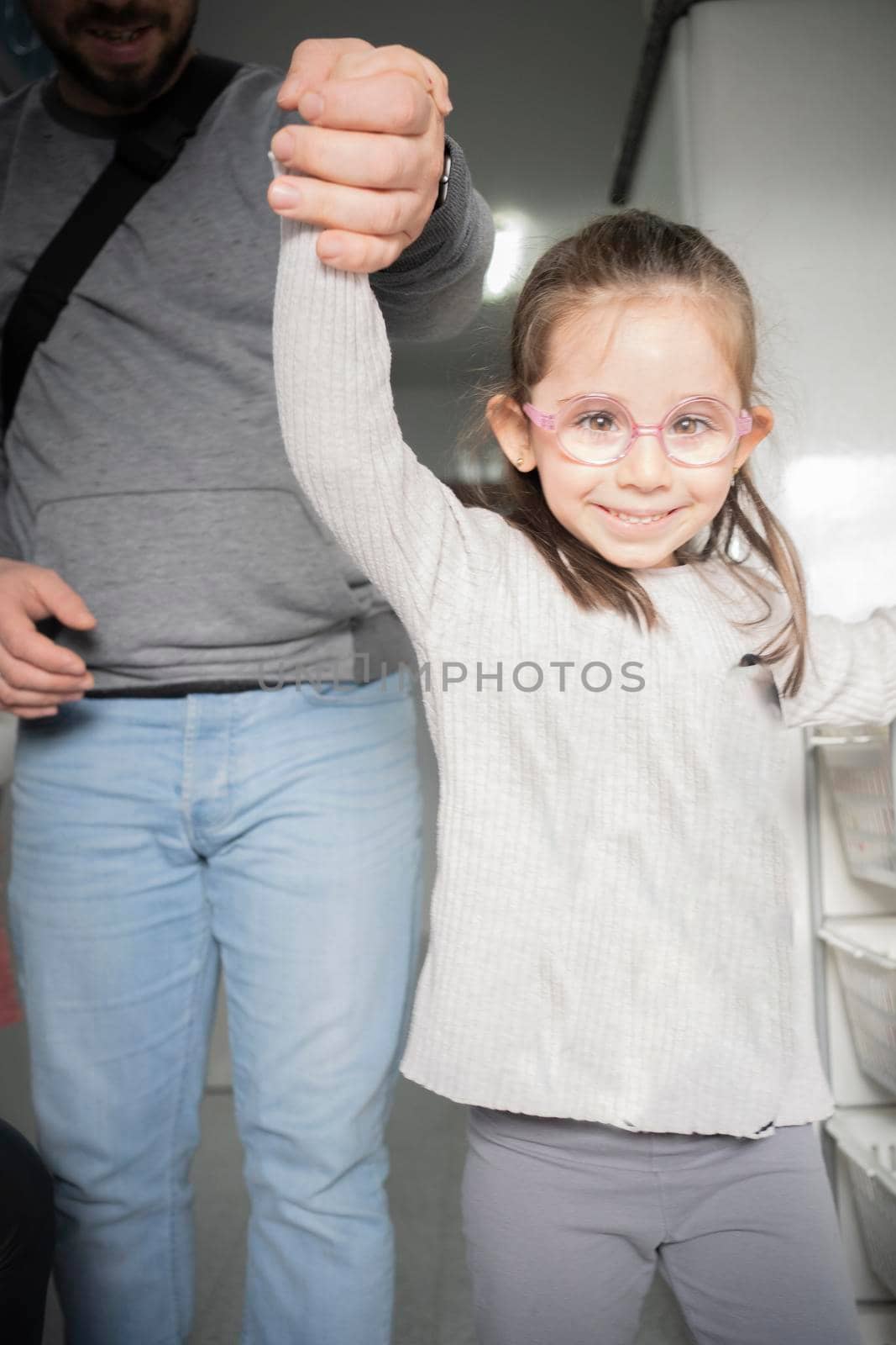 little girl with glasses holding her father's hand by barcielaphoto