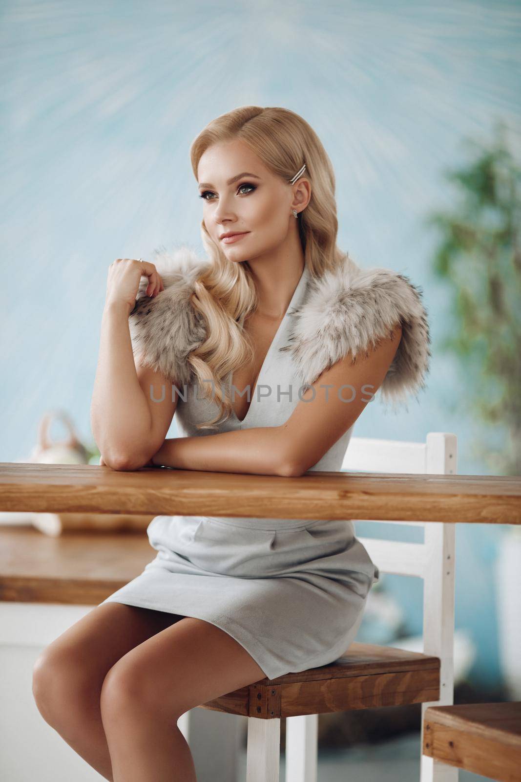 Smiling fashion beautiful woman sitting on bar counter full shot. Happy fashionable young girl at restaurant having positive emotion