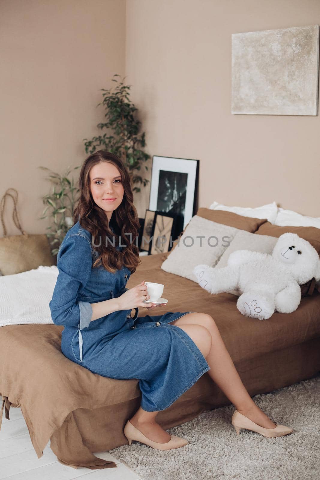 Portrait of gorgeous brunette young woman in casual denim dress embracing her lovely son in denim shirt on the bed. Family and motherhood concept.