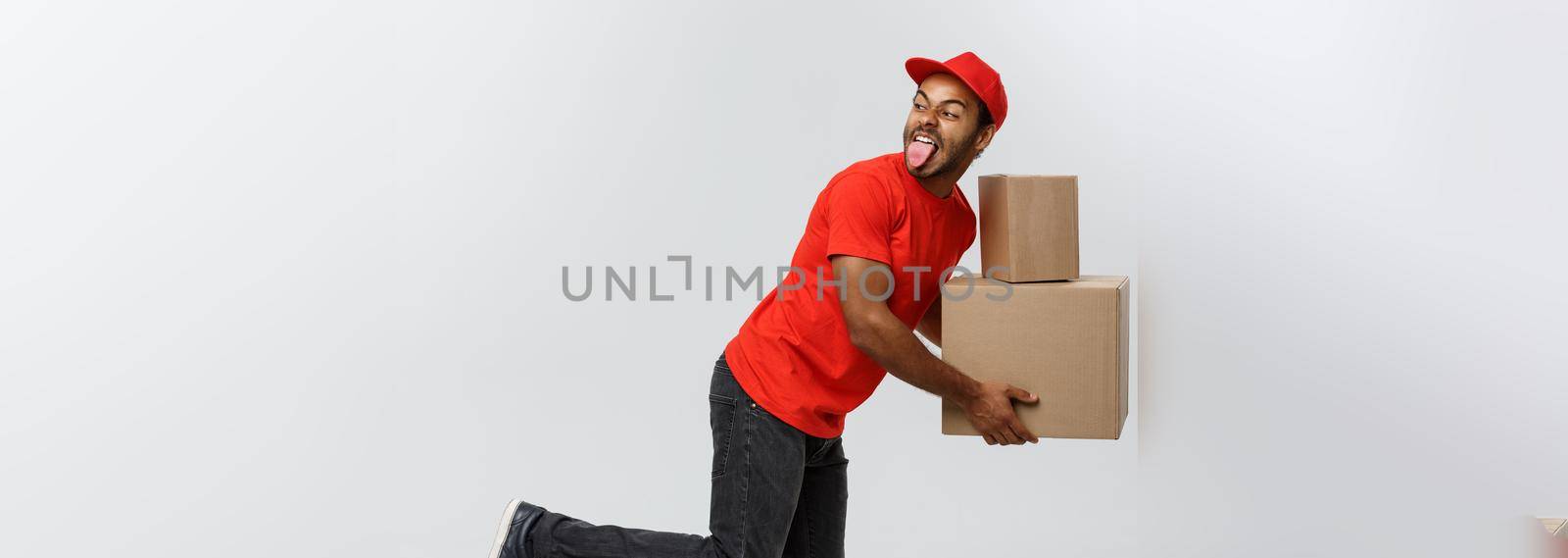 Delivery Concept - Handsome African American delivery man rush running for delivering a package for customer. Isolated on Grey studio Background. Copy Space