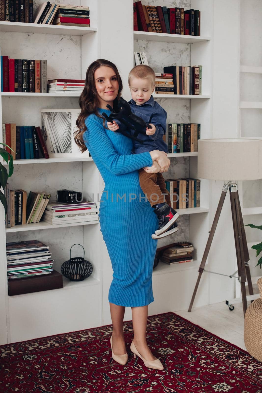 Gorgeous loving mum in blue dress with her son in living room. by StudioLucky