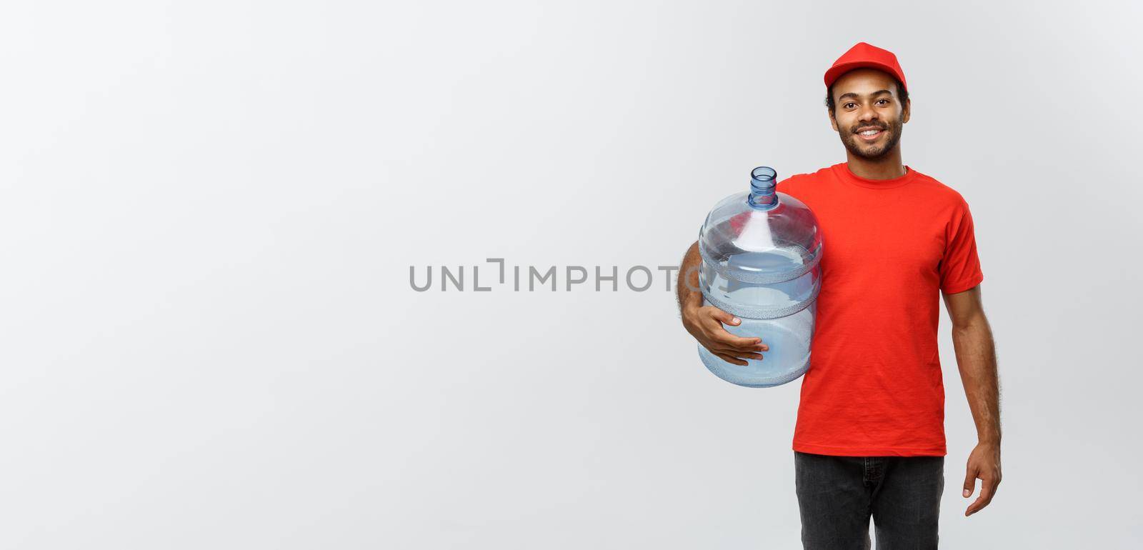 Delivery Concept - Handsome African American delivery man holding water tank. Isolated on Grey studio Background. Copy Space