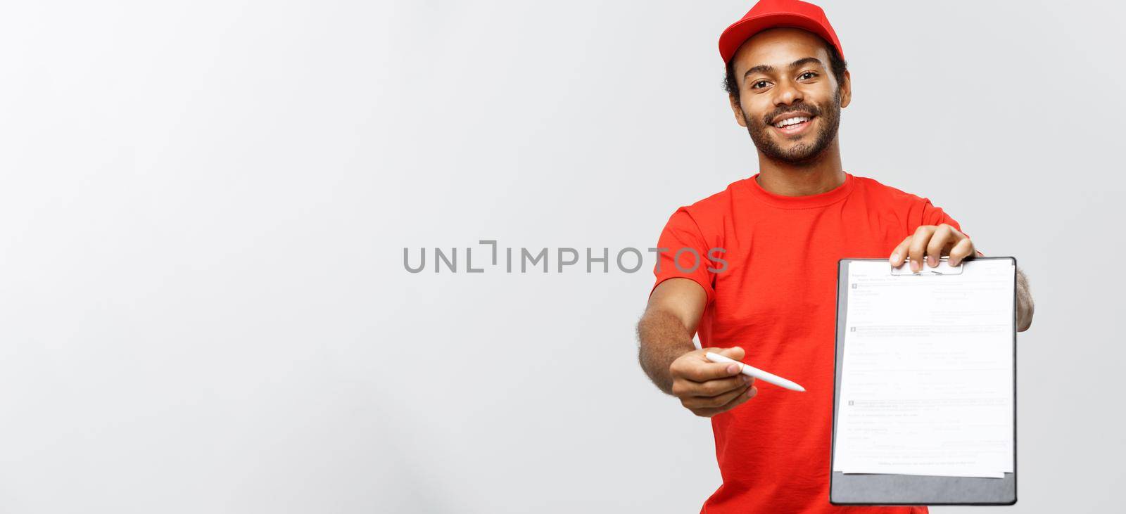 Delivery Concept - Portrait of Handsome African American delivery man or courier showing a confirmation document form to sign. Isolated on Grey studio Background. Copy Space