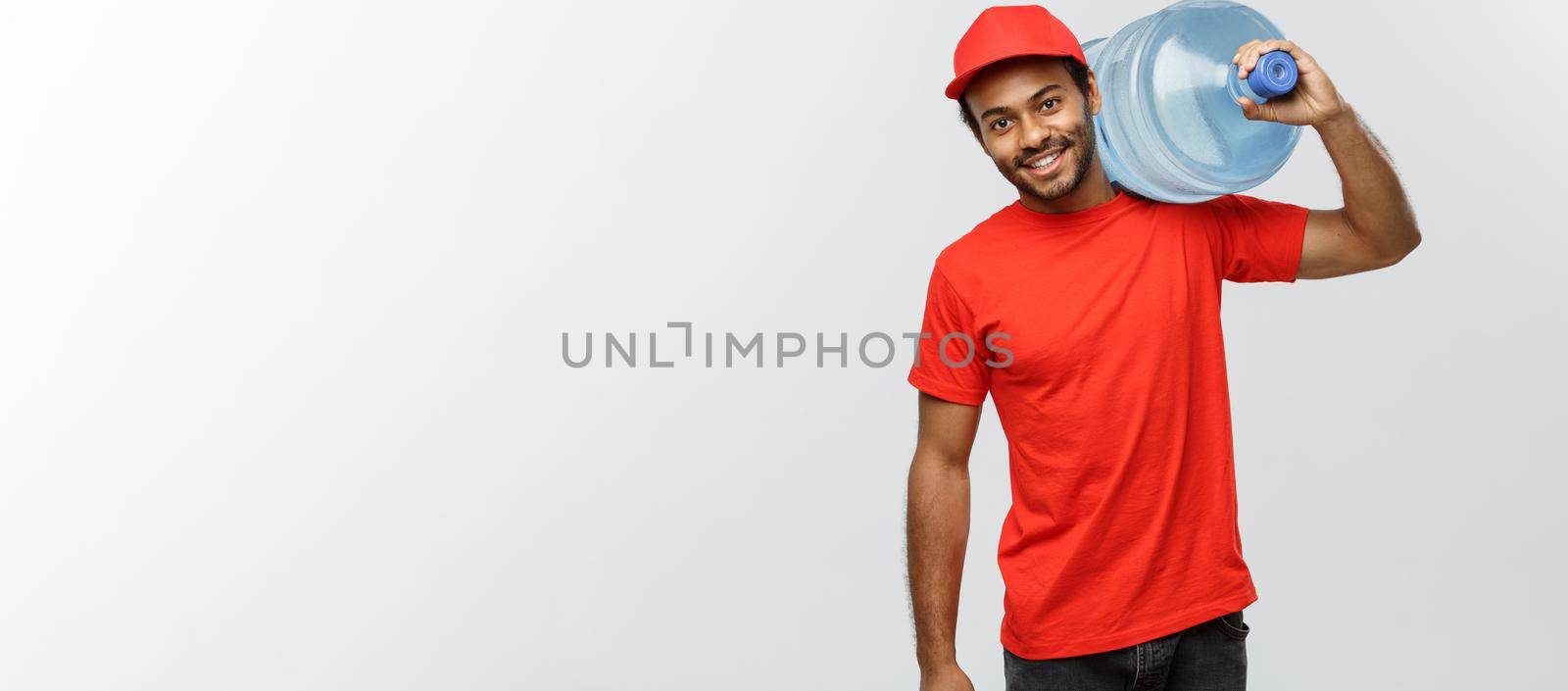 Delivery Concept - Handsome African American delivery man holding water tank. Isolated on Grey studio Background. Copy Space. by Benzoix