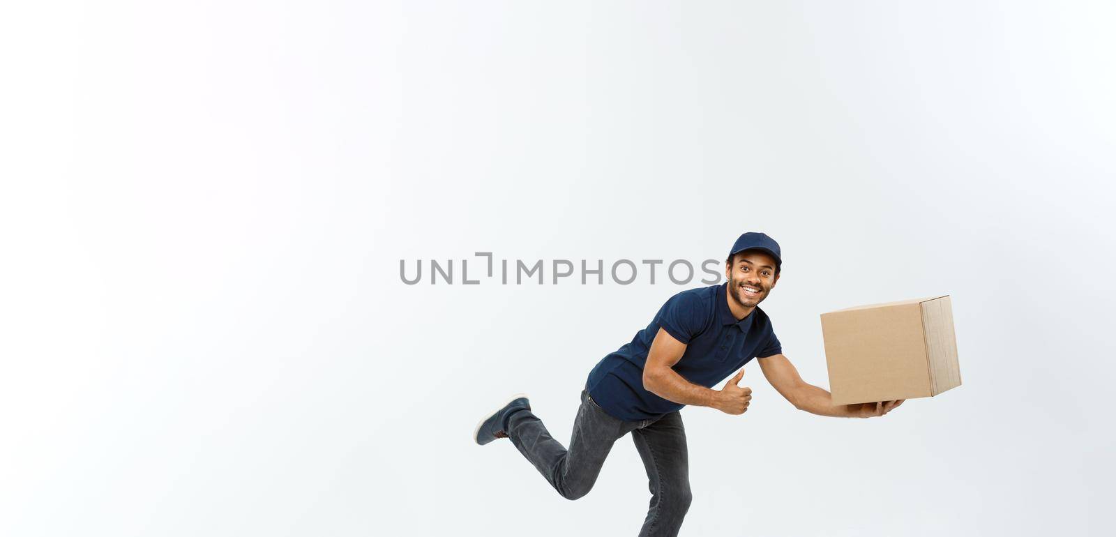 Delivery Concept - Handsome African American delivery man rush running for delivering a package for customer. Isolated on Grey studio Background. Copy Space. by Benzoix