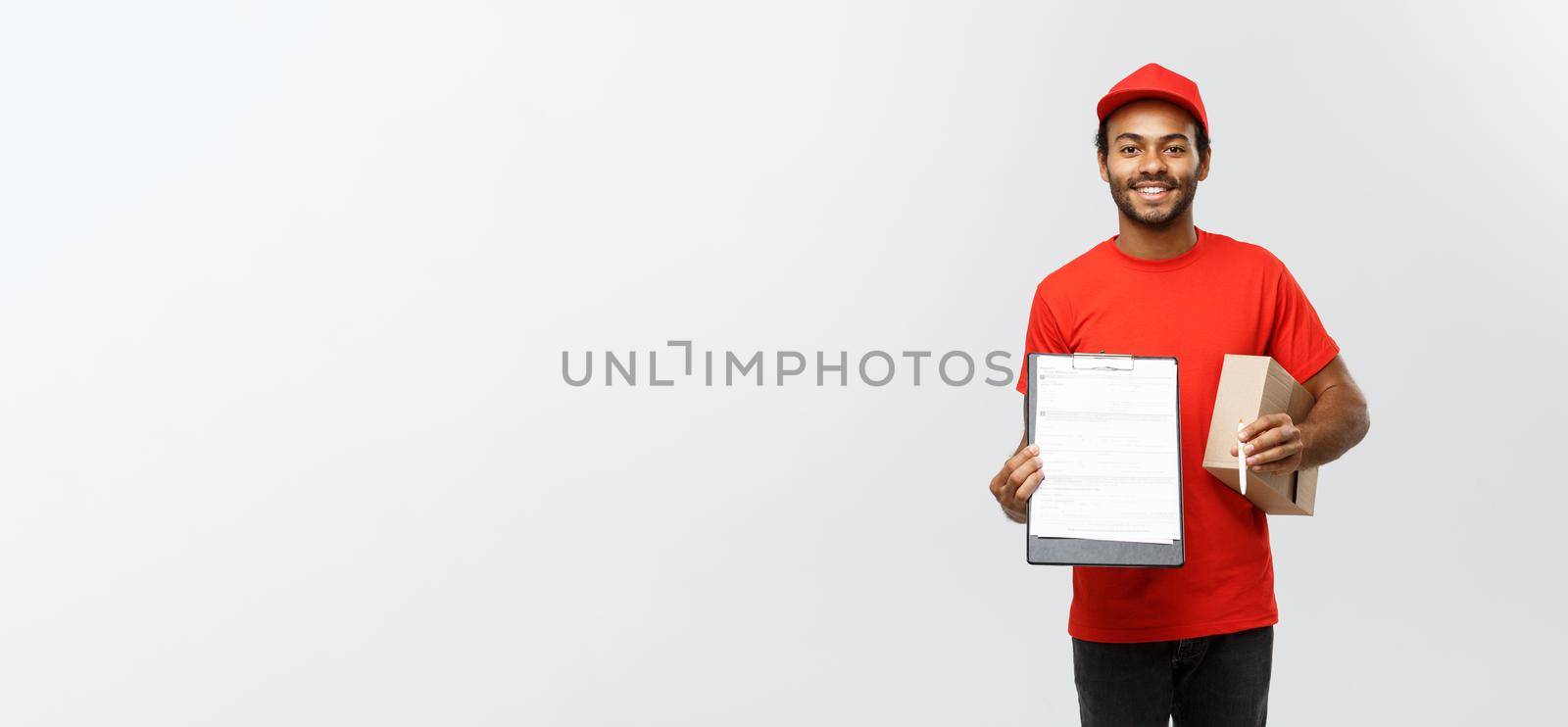 Delivery Concept - Portrait of Handsome African American delivery man or courier showing a confirmation document form to sign. Isolated on Grey studio Background. Copy Space