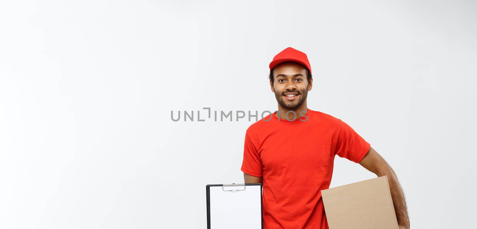 Delivery Concept - Portrait of Handsome African American delivery man or courier showing a confirmation document form to sign. Isolated on Grey studio Background. Copy Space
