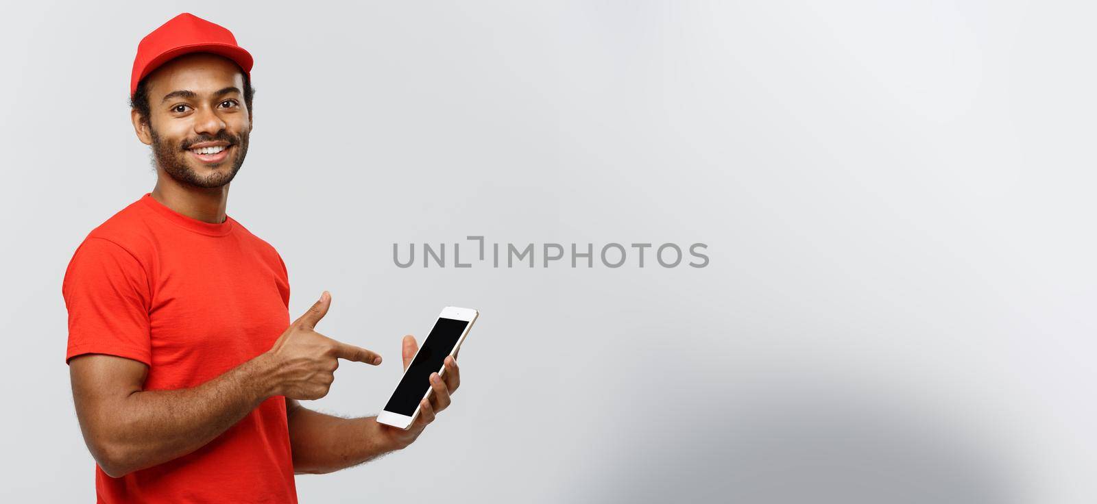 Delivery Concept - Portrait of Handsome African American delivery man or courier showing tablet on you to check the order. Isolated on Grey studio Background. Copy Space