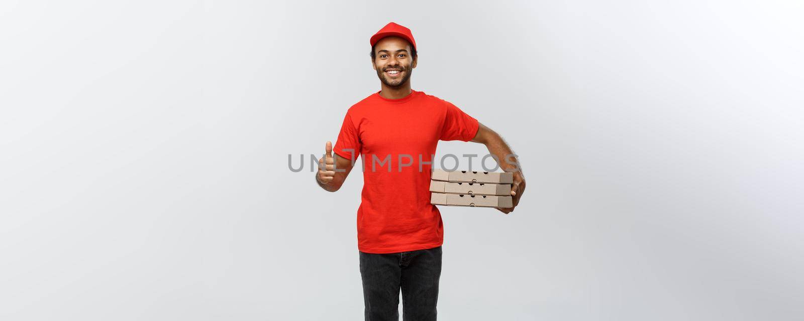 Delivery Concept - Portrait of Happy African American delivery man holding box packages and showing thumps up. Isolated on Grey studio Background. Copy Space. by Benzoix