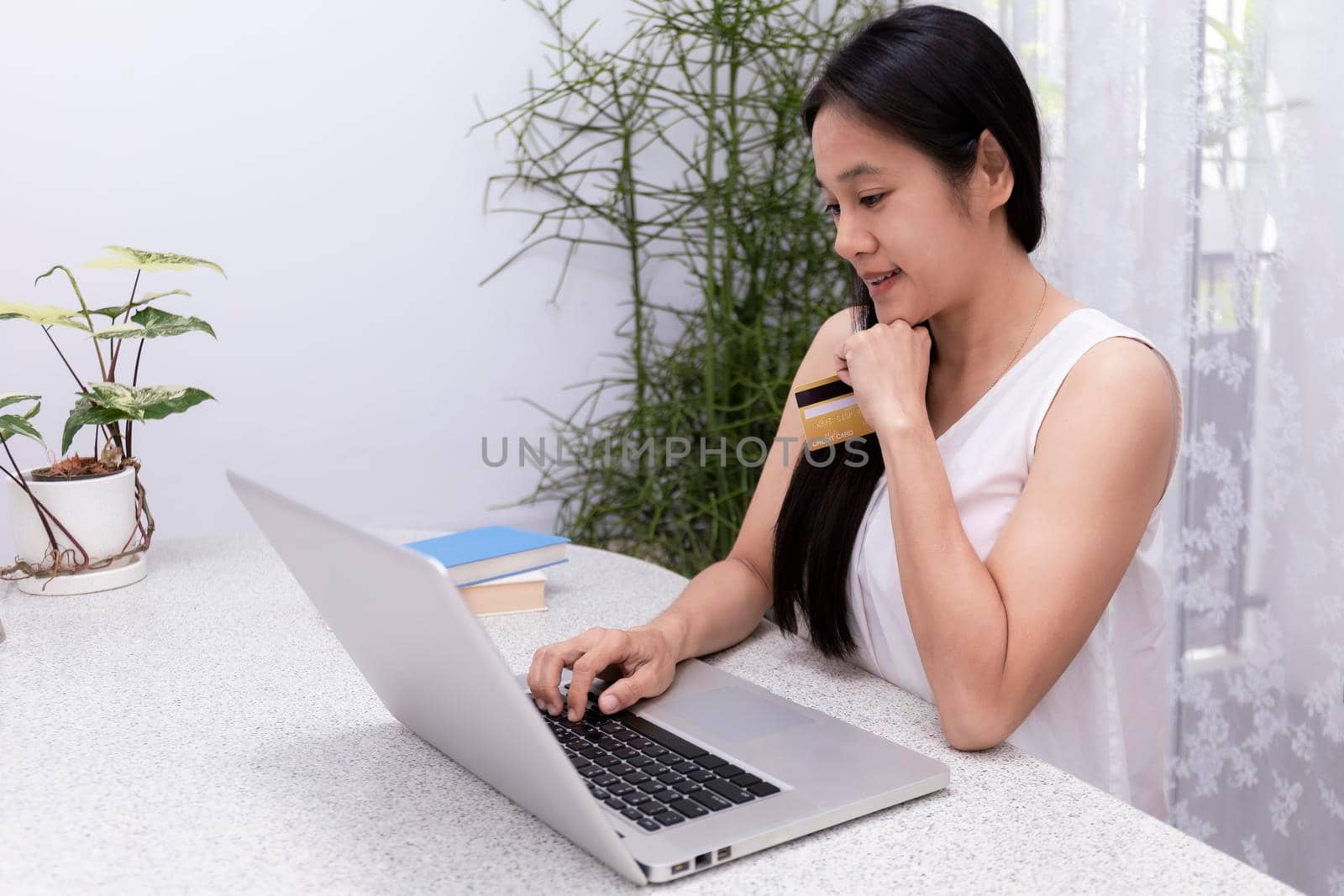 Young woman holding credit card and using laptop computer. Women working at home. Online shopping, e-commerce, internet banking, spending money, working from home concept. Technology shopping online concept.