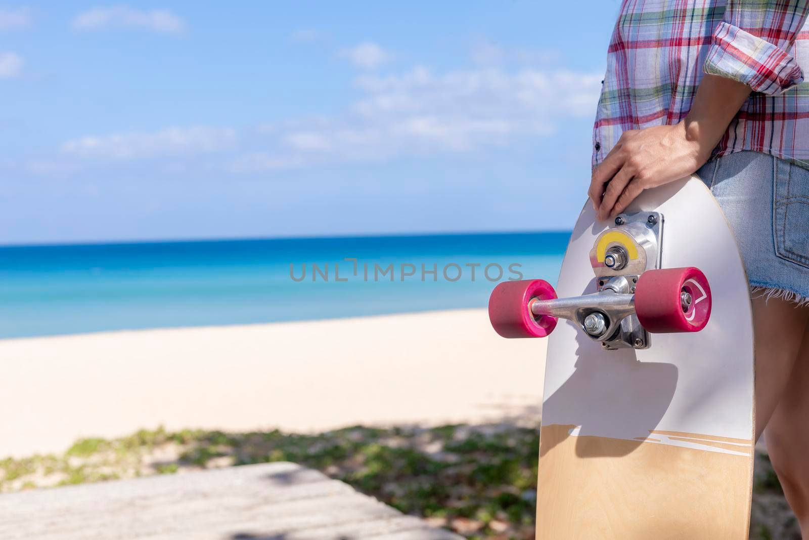 Close up young women hold surf skate board with beach background. Women stand with surf skate relax and enjoy with tropical beach with copy space