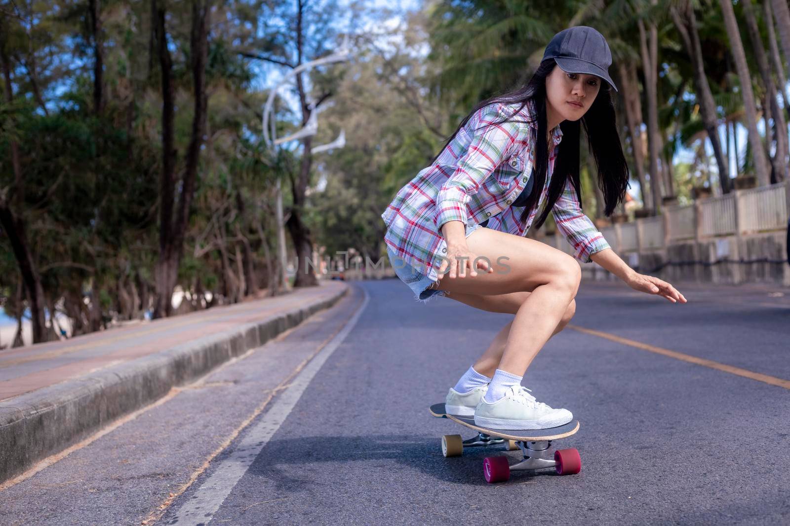 Young asian women play surf skate board at beach road outdoors on morning. Happy women play surfskate board on beach road . Sport activity lifestyle concept