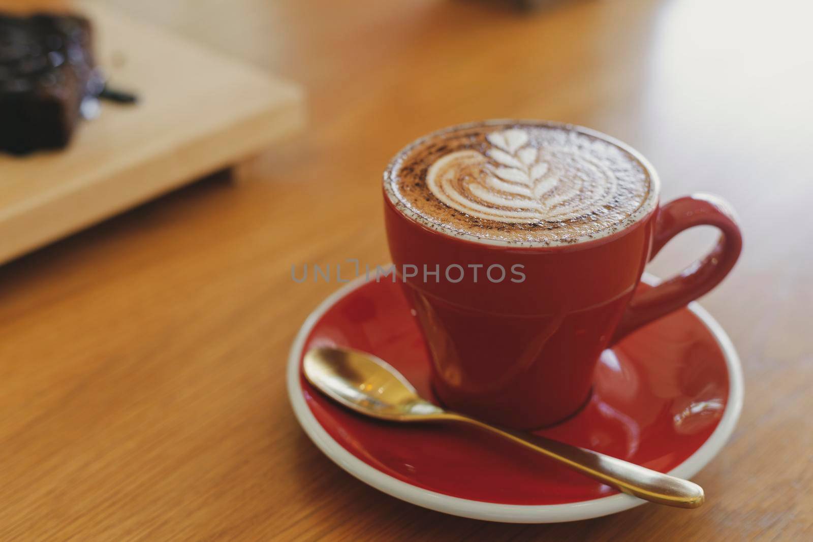 Close up hot cappuccino, latte, caramel macchiato on table with blur coffee shop background. Process with warm vintage tone style. 