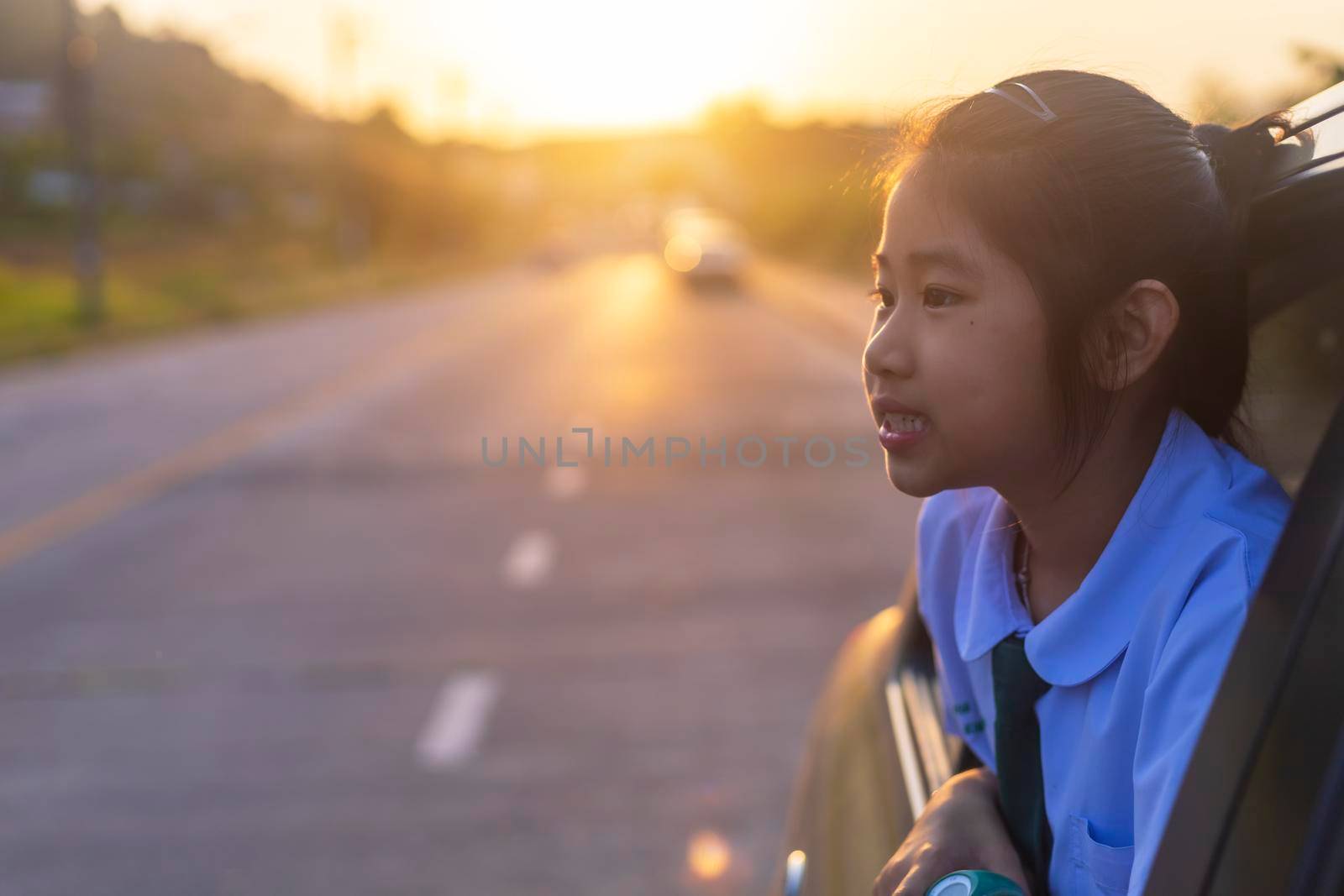 Asian little girl looking something out the car. In the morning, the girl was looking at something outside the car window on the way to school. children relax with street view from the car. Family at car concept. by Satrinekarn