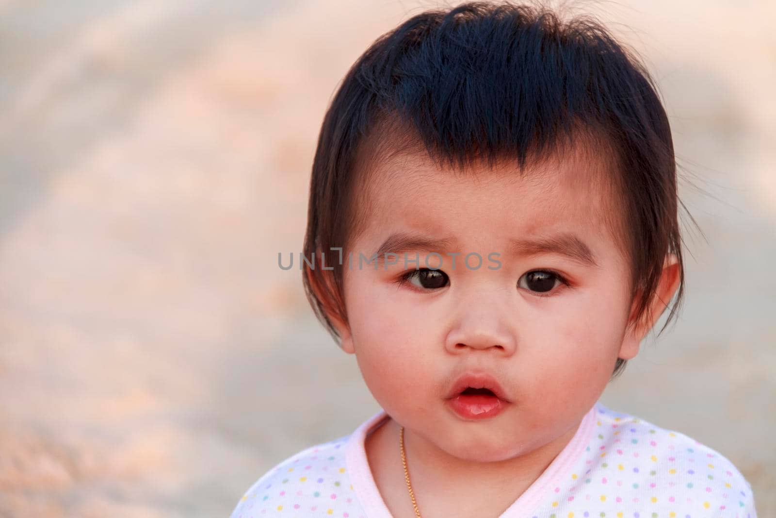 Close up portrait little girl. Cute adorable asian little girl play in park with sun ray background. Happy baby girl play in outdoor park. Close up and soft focus baby gril.