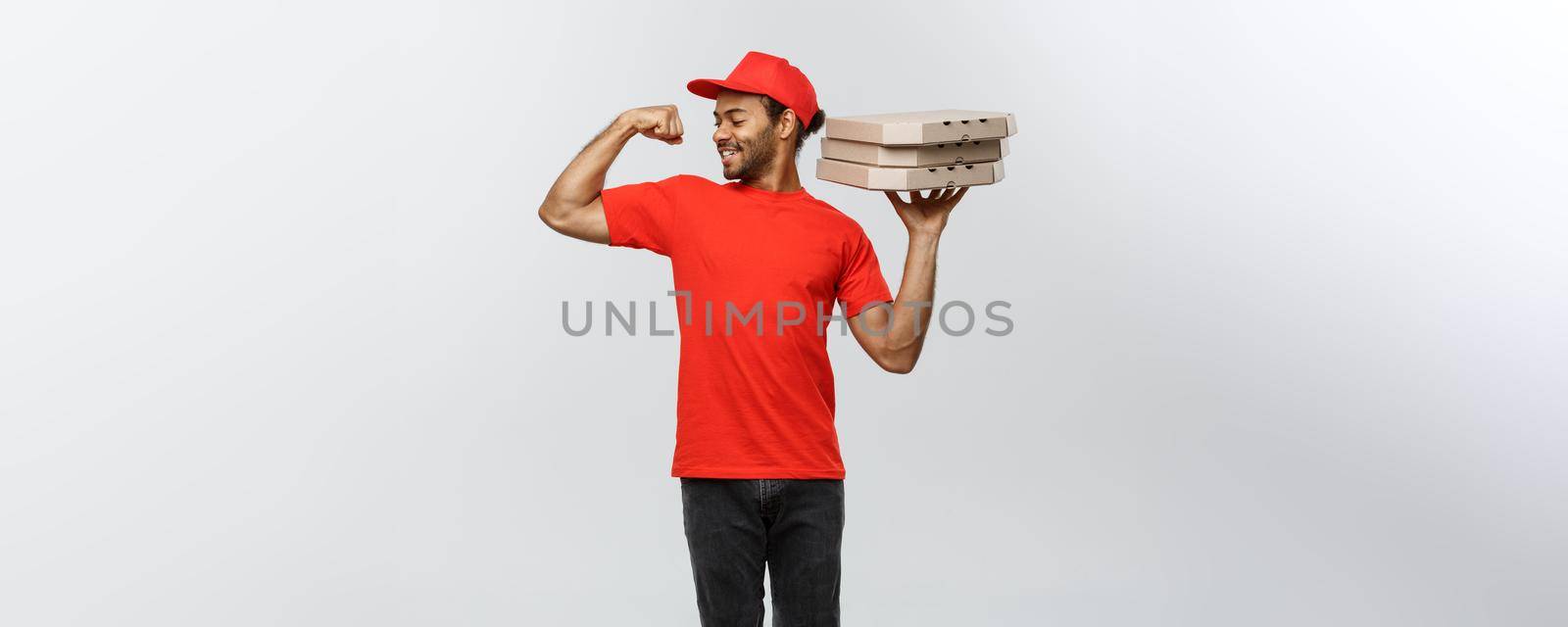 Delivery Concept - Portrait of Strong African American delivery man showing his muscle with pizza box packages. Isolated on Grey studio Background. Copy Space. by Benzoix