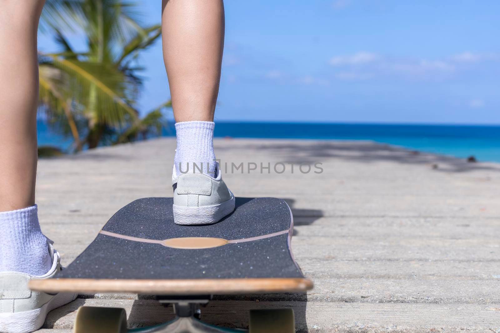 Close up Young asian women play surf skate board at beach road outdoors on morning. Happy women play surfskate board on beach road . Sport activity lifestyle concept