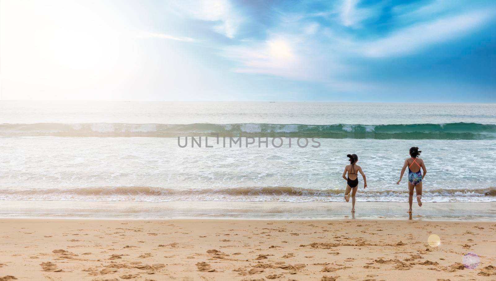Stop motion happy two children wear swimwear running from beach to the sea. Happy family holiday summer concept. Two girl running to beach with copy space